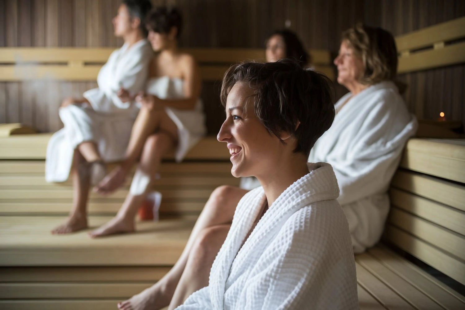People in white robes sitting in a wooden sauna